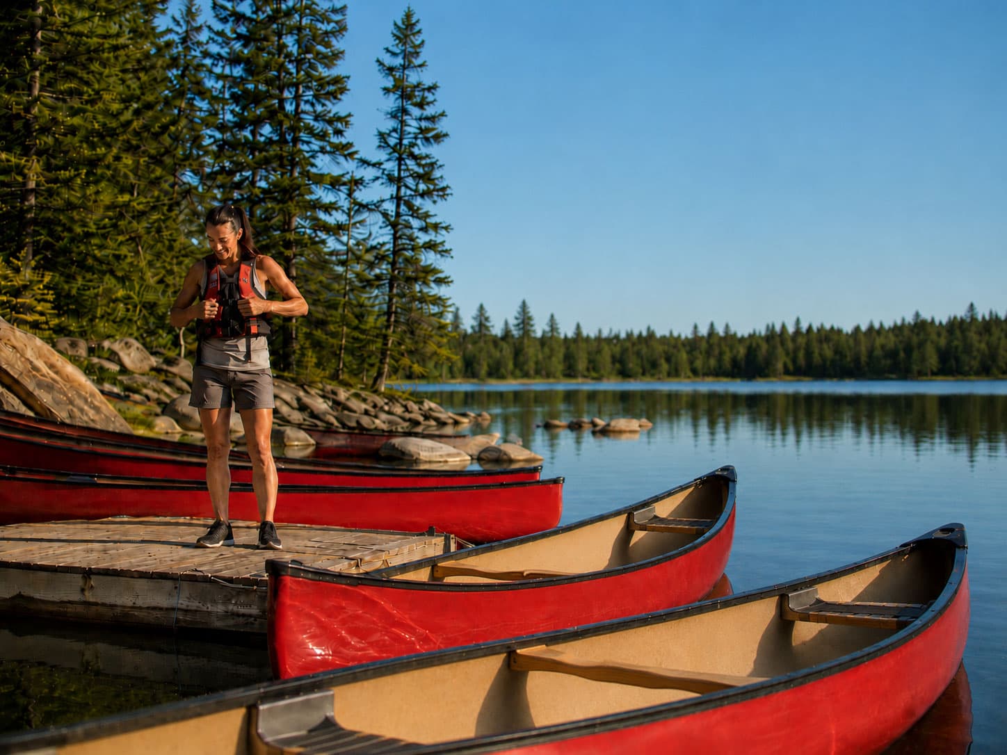 A paddler preparing gear at the water's edge before a backcountry trip